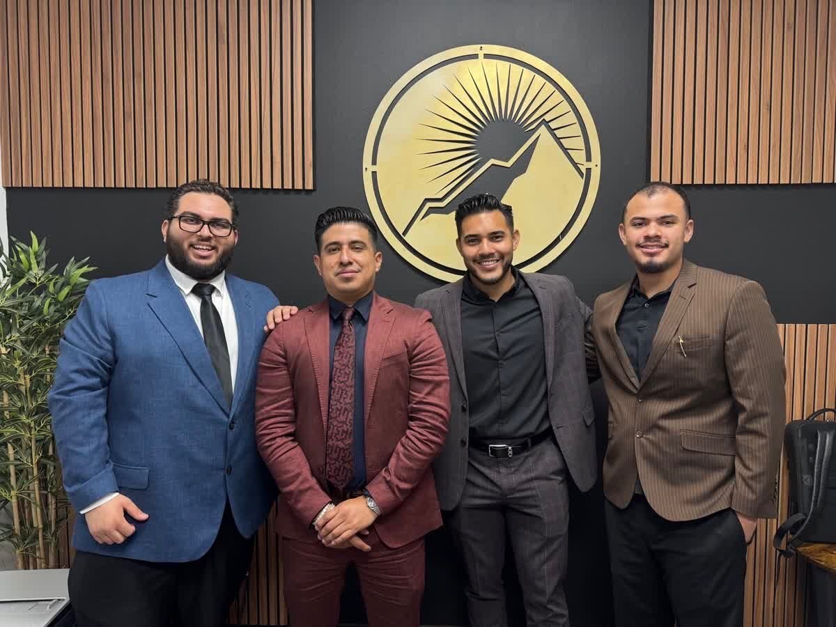 Heritage Ventures Inc. team members standing in front of the company’s gold emblem at the El Paso office